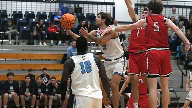 Ali Efe Isik (middle) attempts a layup during a basketball game.