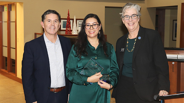 Mariana Ruiz-Gonzales (center) holds an award and stands between Rob Blethen (left) and Sarah Bolton (right).