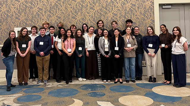 A large group of people stand together in a conference room.