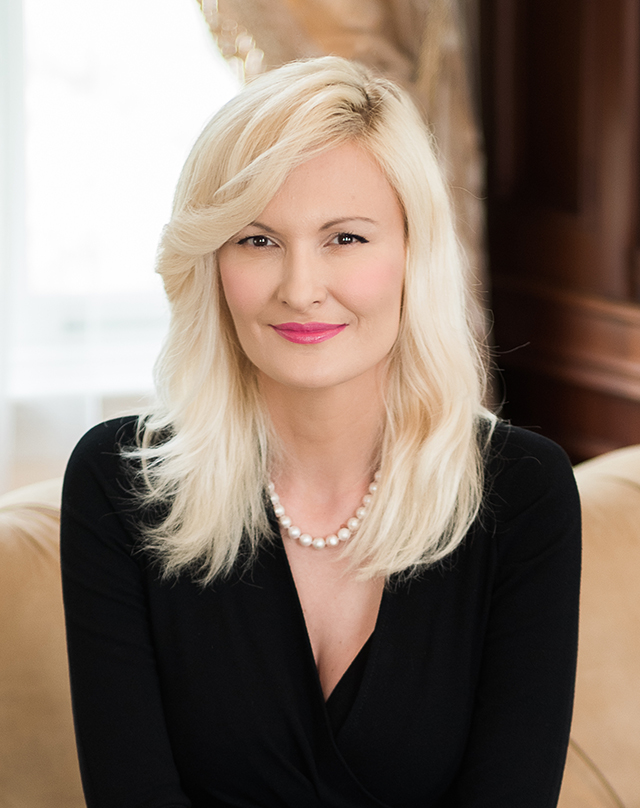 Portrait of Dr. Amra Sabic-El-Rayess with light blond hair, wearing a black outfit and a string of pearls.