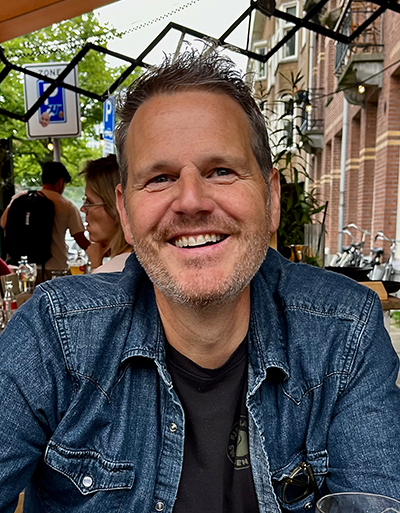Profile of Jason Pribilsky, seated at an outdoor cafe.