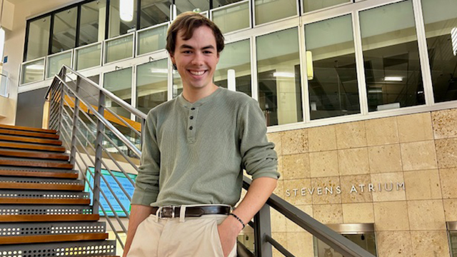 Chase Schubert, standing on the stairway in the Hall of Science atrium.