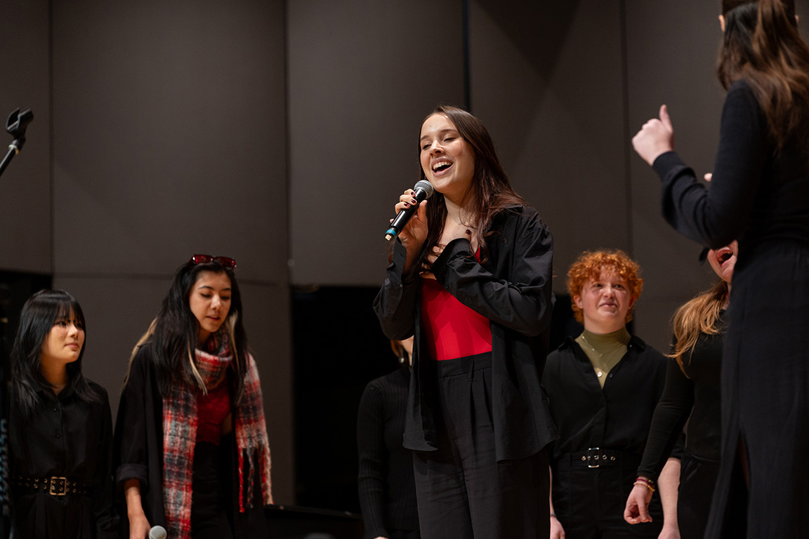 Students singing on stage at Cordiner Hall.