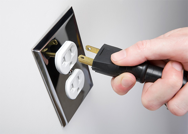 Hand plugging cord into wall outlet.