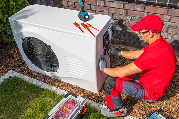 Midland worker installing a heat pump outside a house.