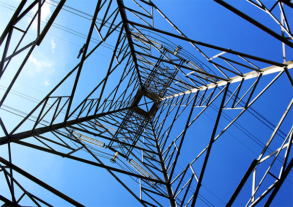 Image looking up at sky though the center of a transmission tower.