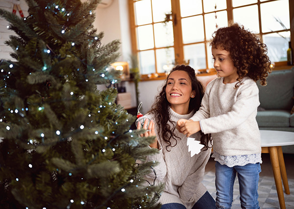Mother and daughter handing ornaments on a Christmas tree.