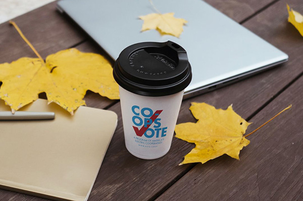 Coffee cup that says ''Co-ops Vote'' sitting on wooden table.