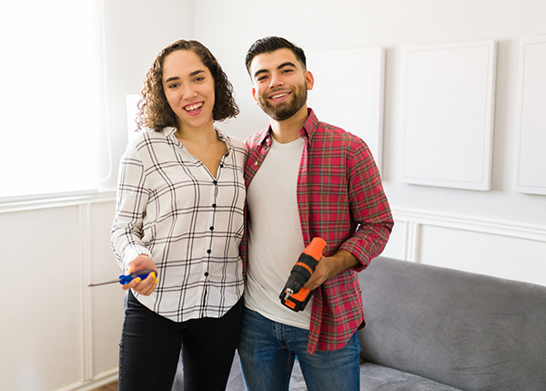 Happy couple holding tools at home.