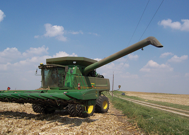 Combine harvester parked in a field next to a power line.