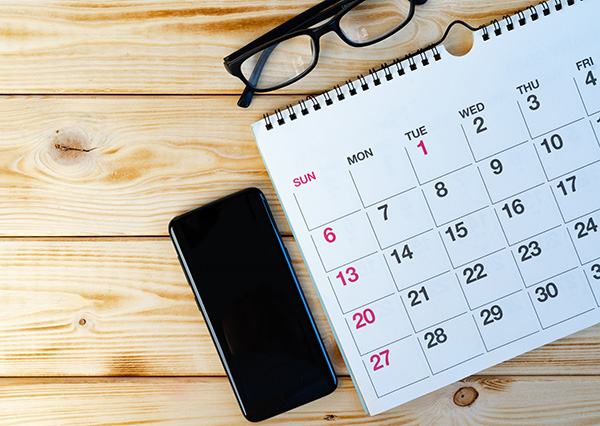 Calendar on table next to glasses and smartphone