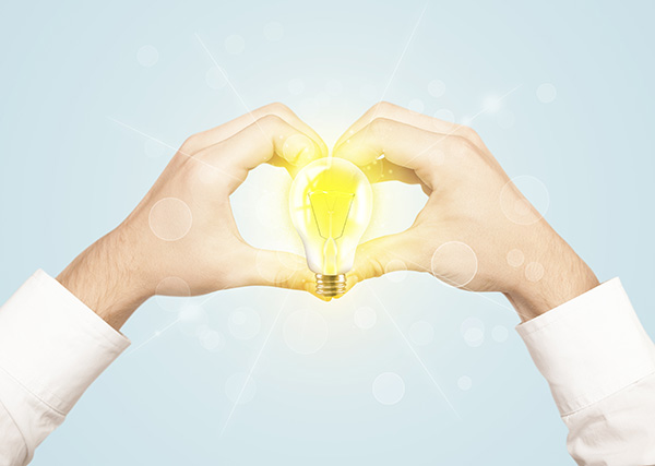 Hands making a heart shape with a lightbulb in the middle.