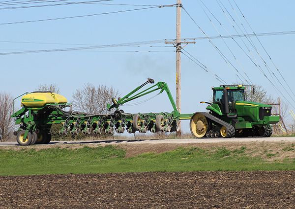 Farm equipment driving on side of rural road.