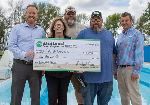 Group of people presenting big Midland check in front of pool.