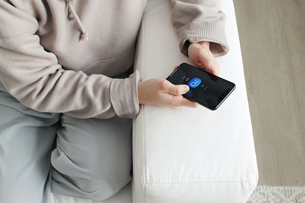 Person in sweatshirt adjusting thermostat from smartphone.