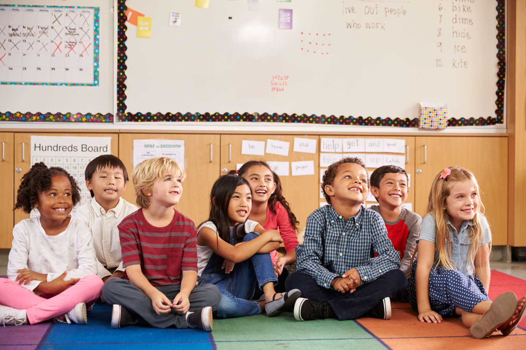 Young children smiling, sitting on classroom floor