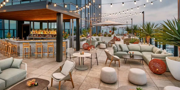 Sunny rooftop deck with sofas, tables, and patio umbrellas