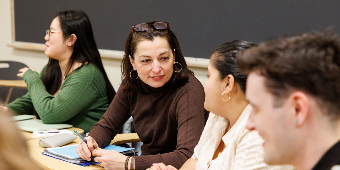 Four students sit at at desks discussing the day's lesson
