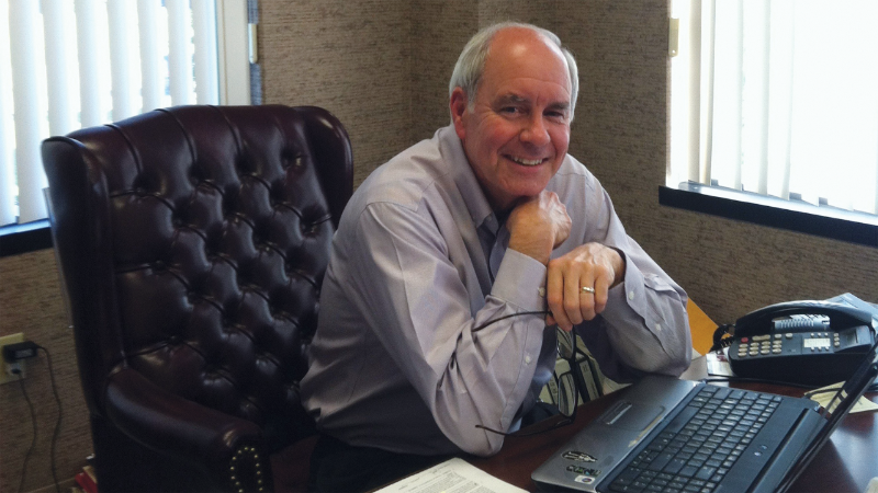 Rodd Fussinger smiling while sitting at his desk