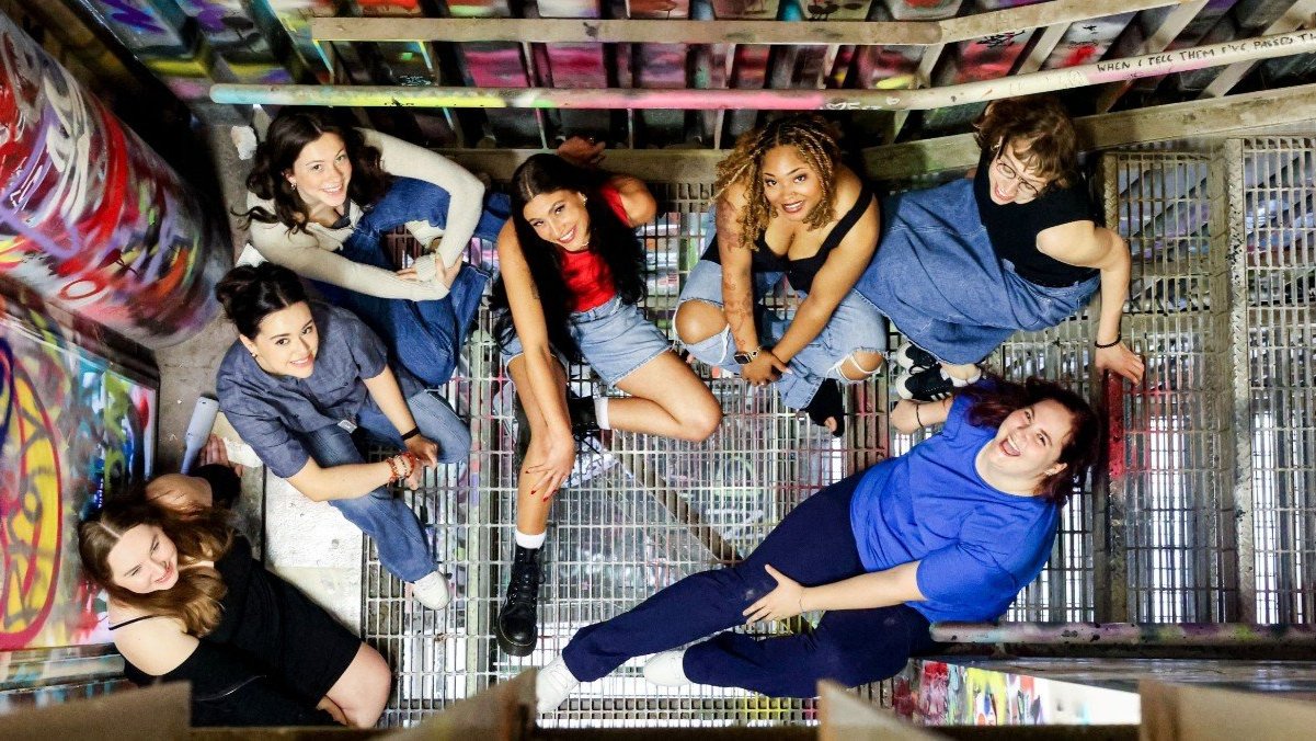 Group of DAAP students sitting on metal stairs with graffiti walls