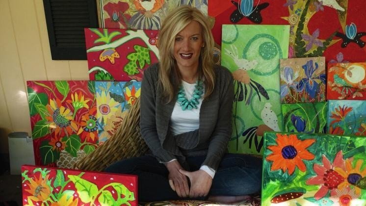  Dr. Sarah Hellmann sitting amongst colorful paintings