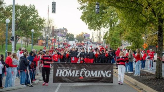 University of Cincinnati Homecoming parade with a banner and a crowd in red and black.