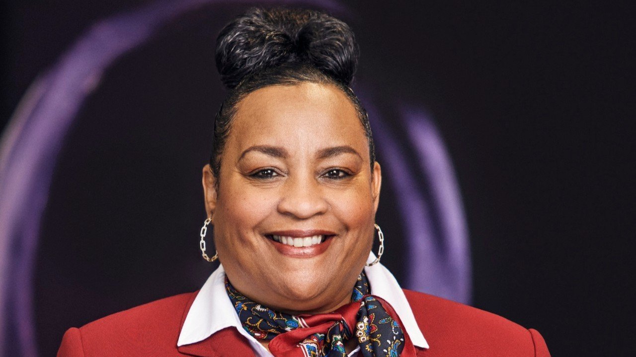 Monica Turner, smiling in front of a dark background.