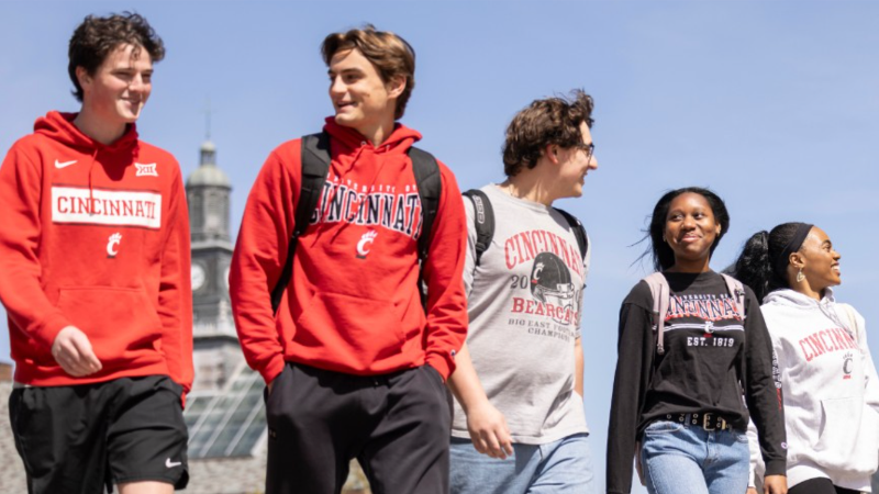 Five students on campus wearing UC shirts