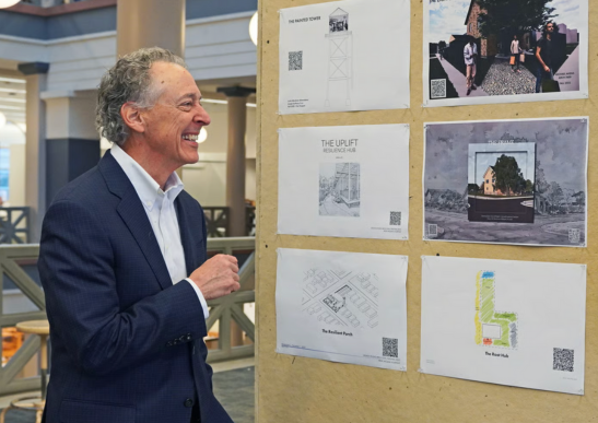 Image of Bill Dupont smiling as he looks at an exhibit. 