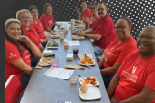 UH staff wearing red and eating together at a table.