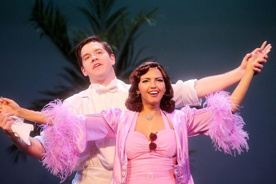 Aman and woman in pink dress with arms outstretched.