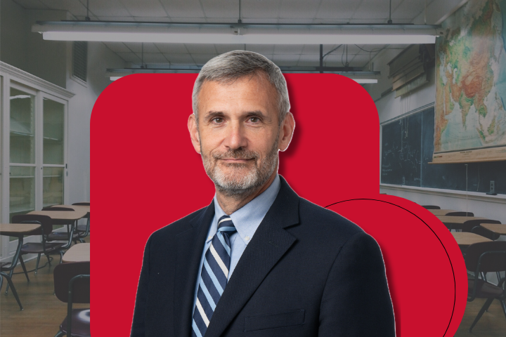 Image of education policy expert Robert Pondiscio in suit with classroom backdrop behind him