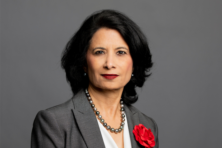 Image of President Renu Khator in grey suit with red flower on coat