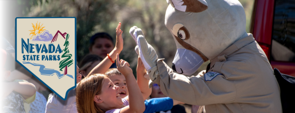 a mascot of a fox, Carson Kit Fox, wearing a ranger uniform and high-fiving a group of children