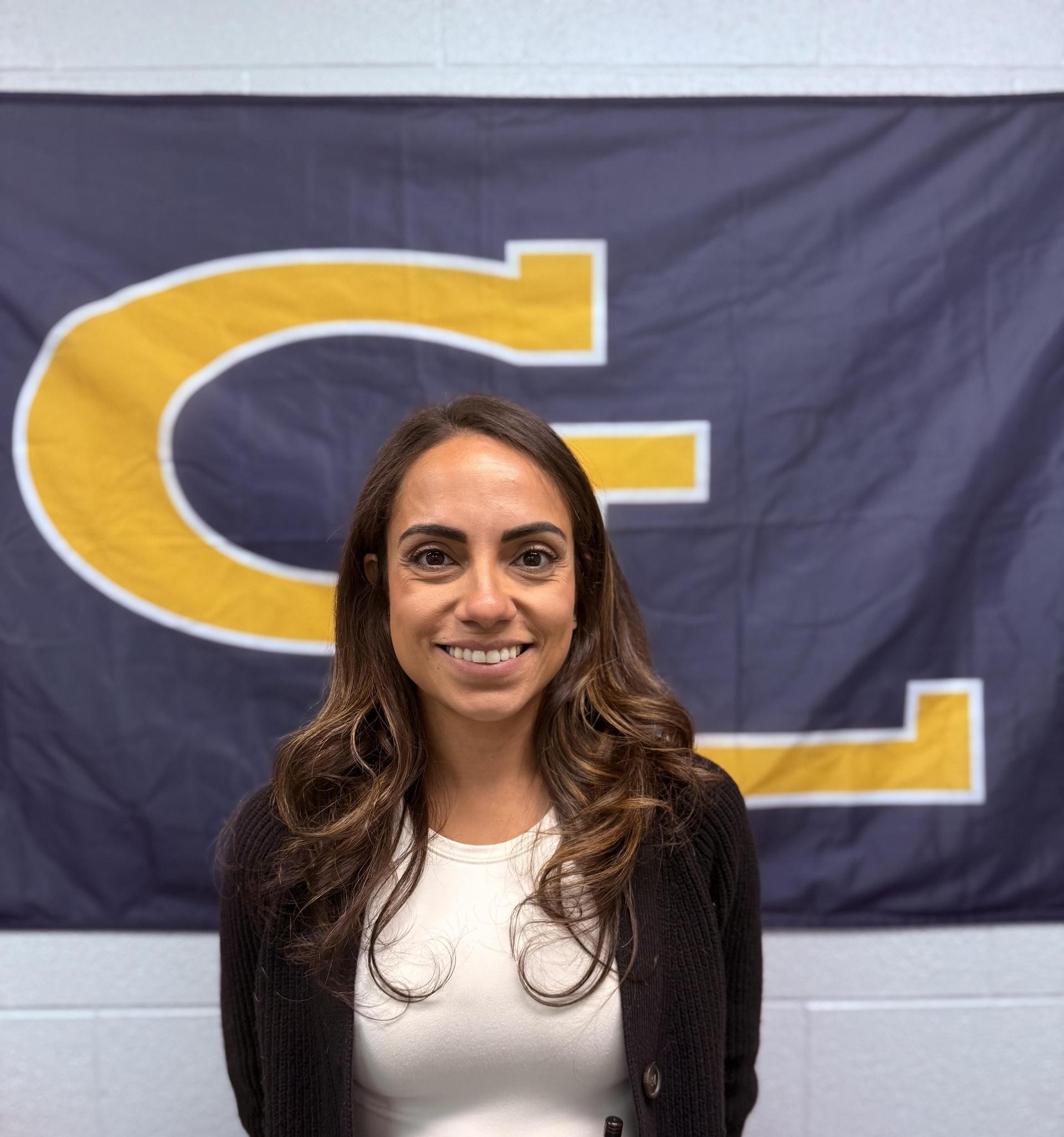 Picture of a smiling Sally in front of a Grand Ledge Banner