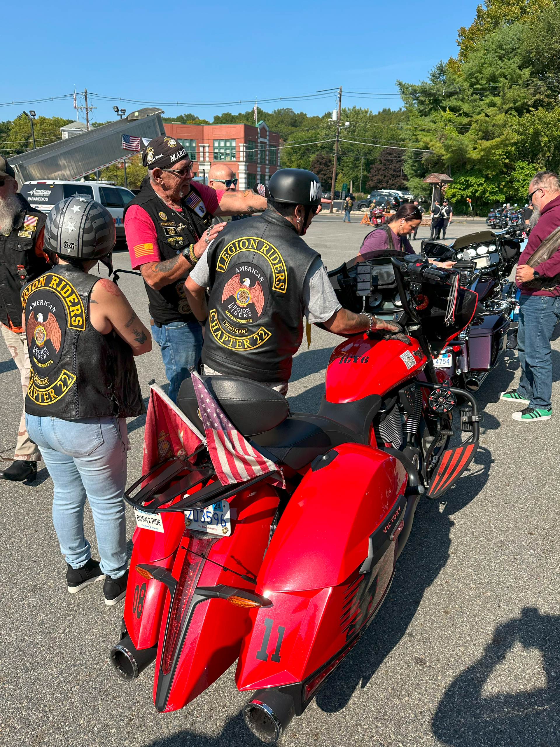 a group of people standing next to a red motorcycle