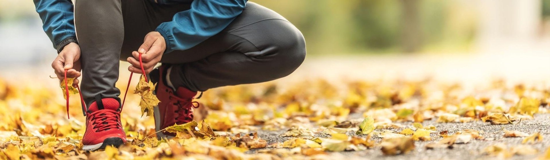 an image of a person tying their shoes on Fall leaves