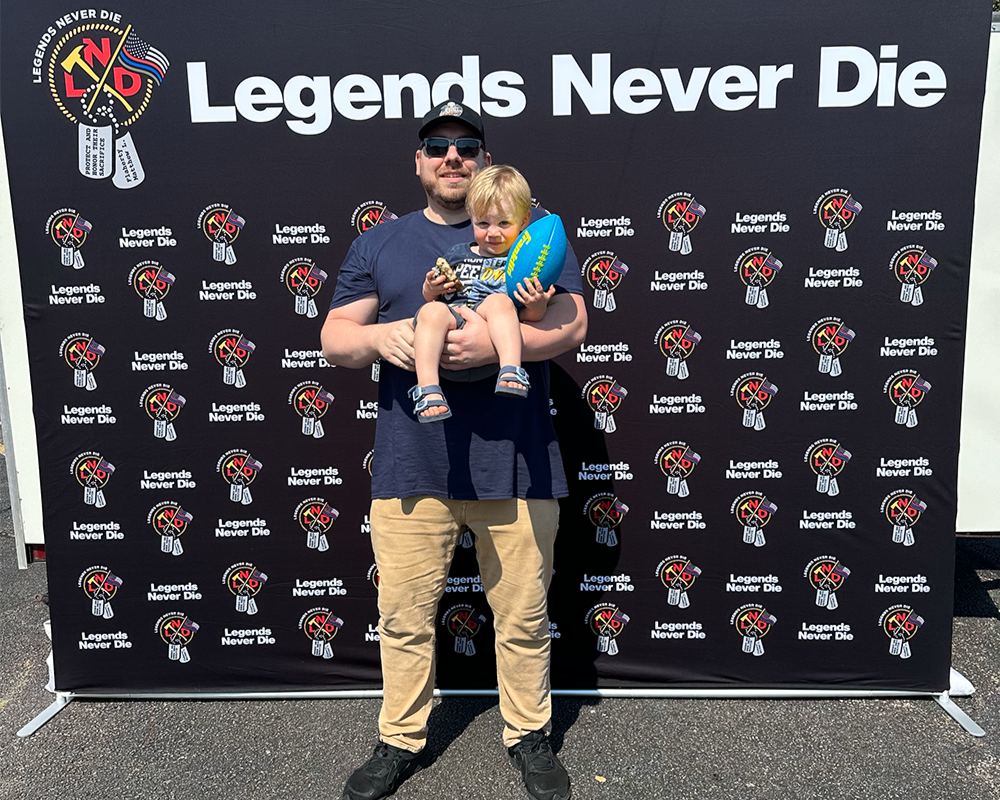 a man holding a child in front of a wall with logos