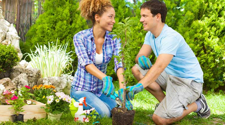 Young Ogden Utah couple planting flowers in the garden of their first home representing the rewards of homeownership