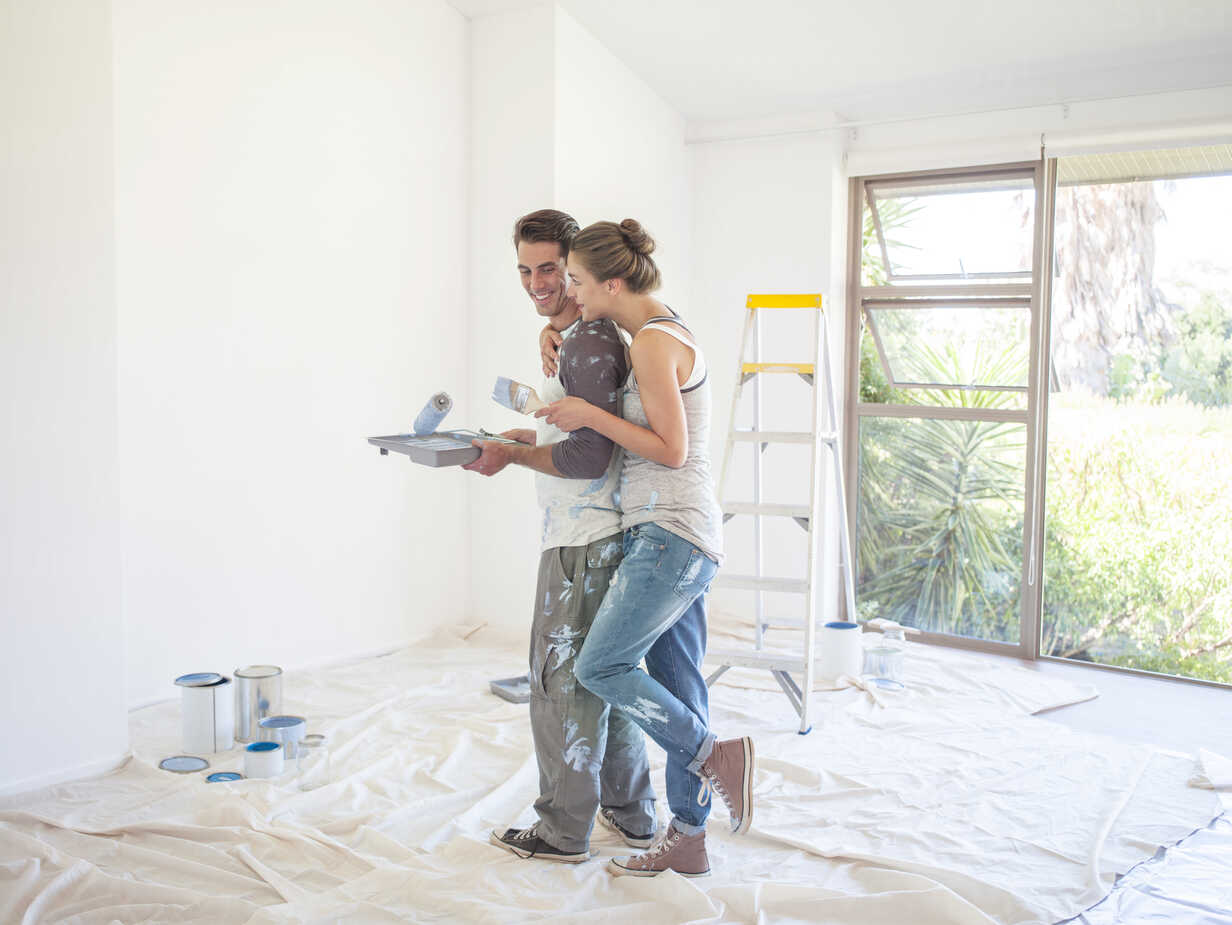 Ogden Utah couple painting a wall in their first home after purchase showing the joy of homeownership and making a space their own