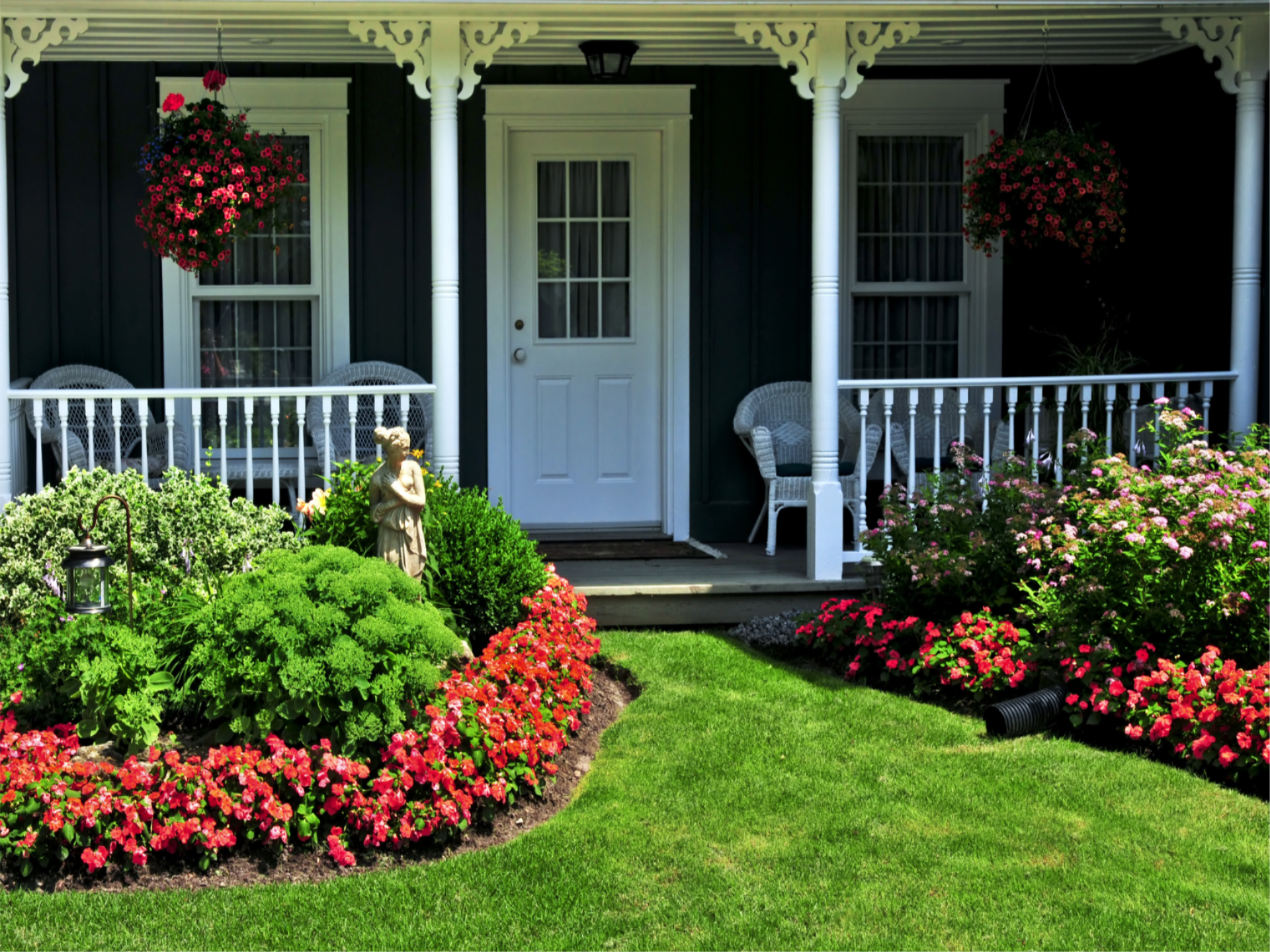 Exterior image of a front porch with vibrant spring flowers and green grass.