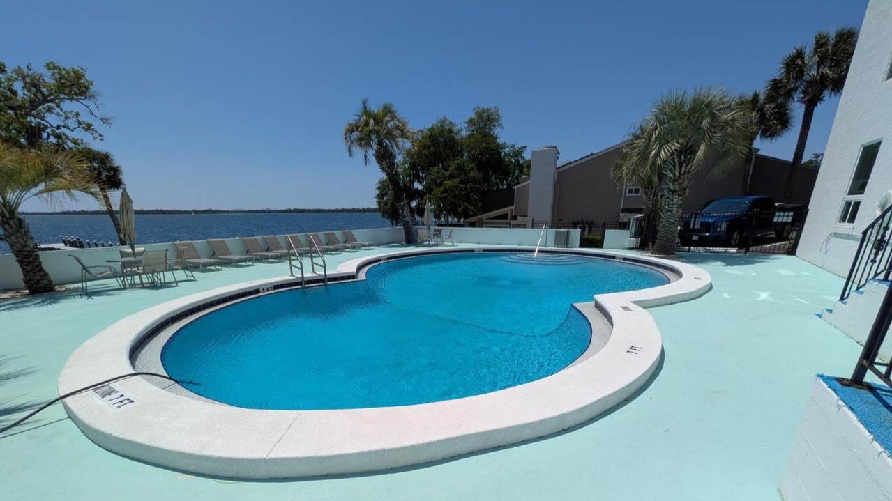 the bay club condos pool with views of the bay in the backgroun the bay club condos pool with views of the bay in the backgroun