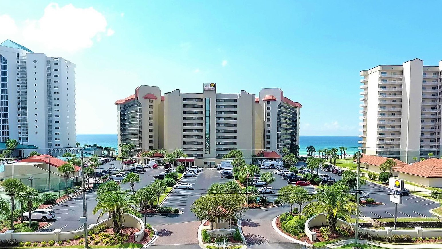 Image of the condo and its parking lot occupied with palm trees