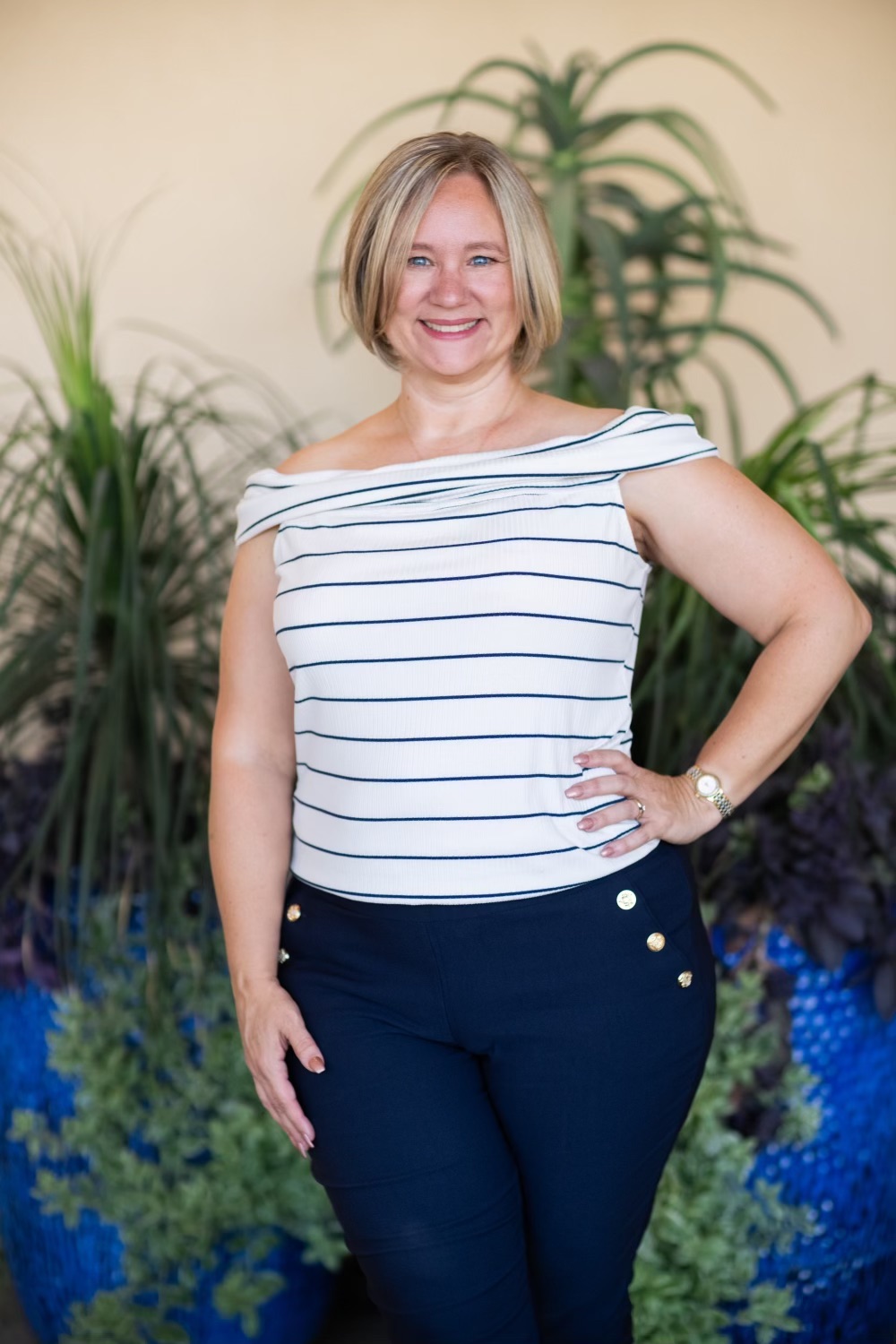 Raysun Frost standing in front of large potted plants smiling