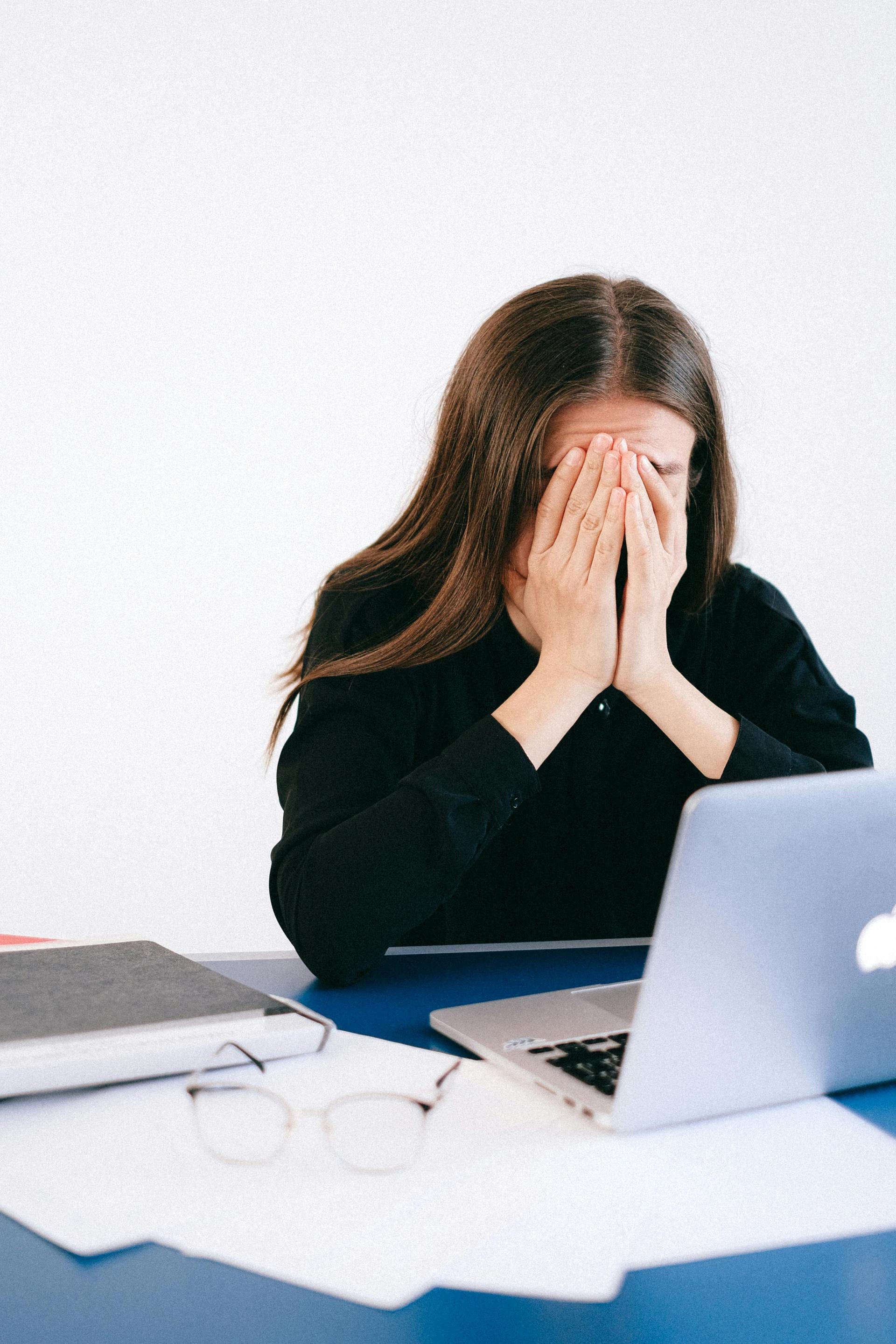 A woman stressed, covering her face in her hands