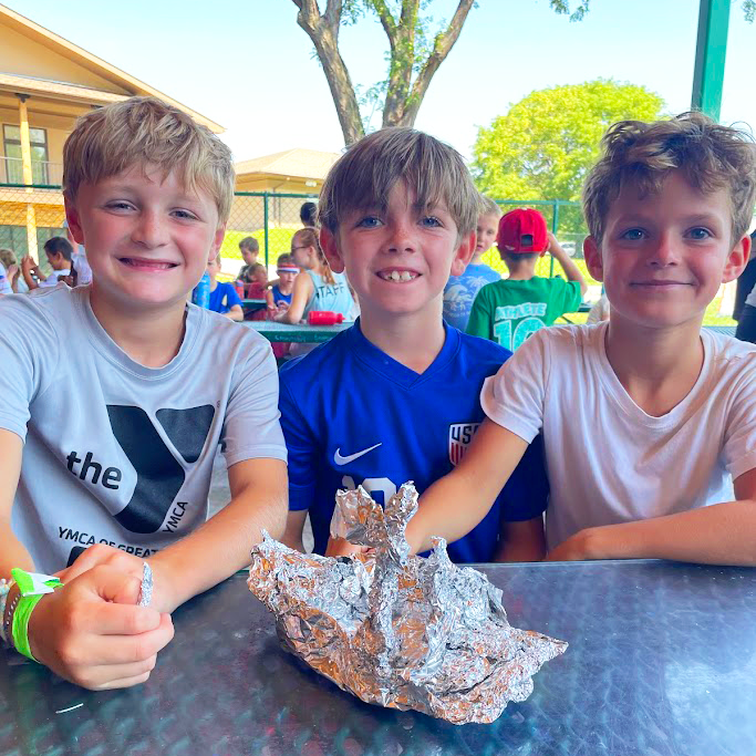 Boys outside on picnic bench doing experiments with tin foil