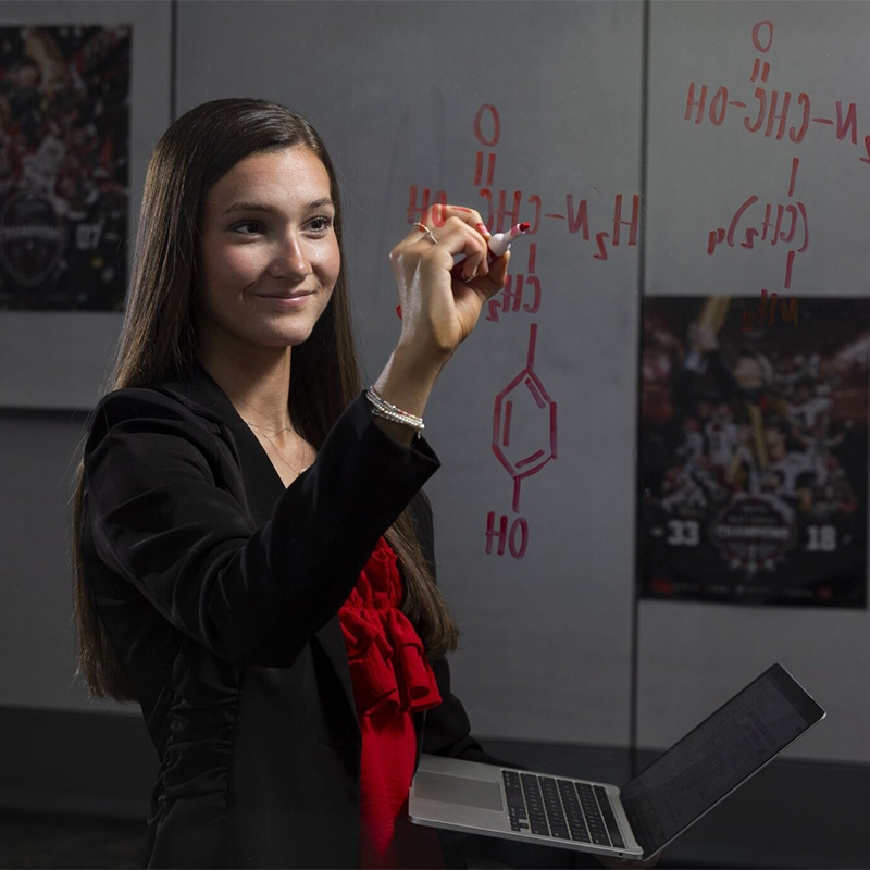 Halley Bynum works out a chemistry problem on a market board.