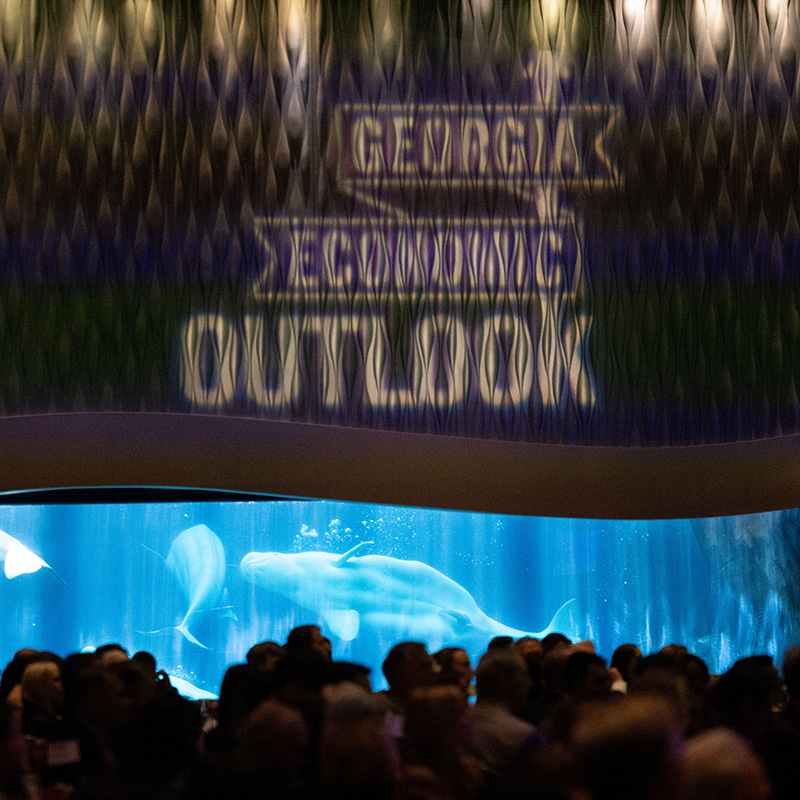 The Georgia Economic Outlook logo projected on a moody aquarium wall.