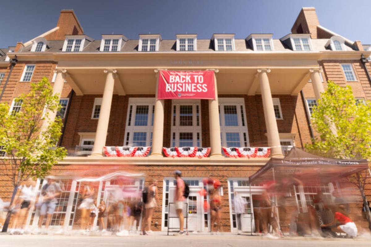 A timelapsed image of students moving in front of Amos Hall with a back to business banner above them.