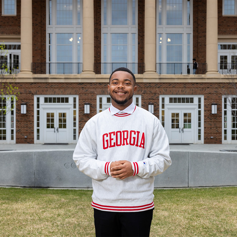 Jakhari Gordon wears a Georgia sweatshirt and poses on the lawn in from on Correll Hall.